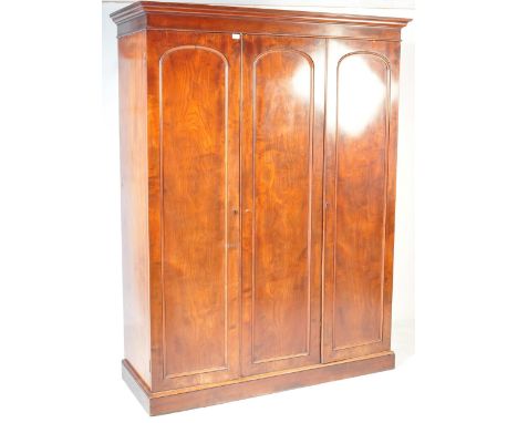 A 19th century Victorian mahogany triple wardrobe compactum. This smaller proportion example being raised on a plinth base wi