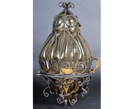 A vintage 20th Century wrought iron and amber coloured glass hanging lantern light having a segmented glass body with scrolle