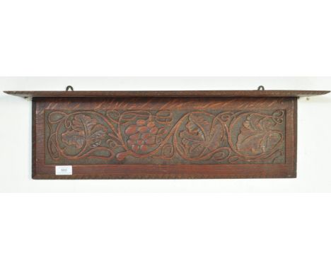 An Edwardian Jacobean revival carved oak shelf. The shelf with lower carved panel depicting grapes, vine, and oak leaves. Abo