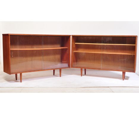 A mid-century teak wood glass door library bookcase cabinet of Danish influence. The cabinet having tapering legs with twin g