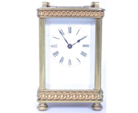 A 20th century brass cased carriage clock. Raised on bun feet with rope twist edges, white emanel dial with roman numeral cha