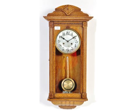An early 20th century oak cased Vienna regulator wall clock having having a carved top with roman numerals to the chapter rin