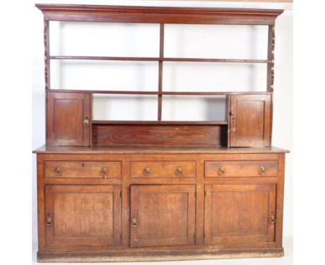 An 18th century George III country oak dresser. Raised on a plinth base with a series of cupboards beneath short drawers abov