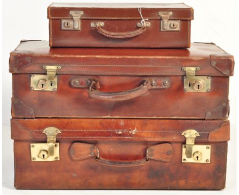 A trio of vintage leather suitcases to include a British made Pakawa briefcase, a travel case with brass lever fixtures and a