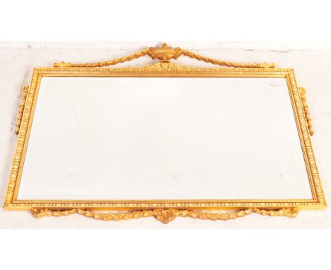 A contemporary gilt framed hanging mirror in the manner of a 19th Century example having a carved urn top with swags and furt