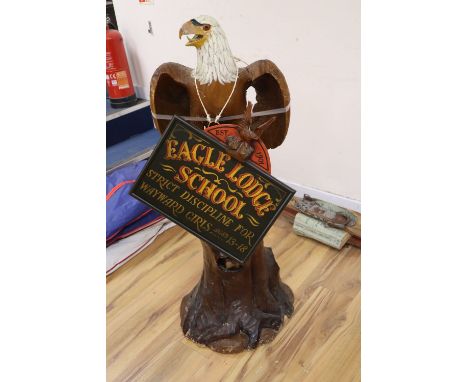 A carved and painted wood model of a Bald Eagle perched on a tree stump and a carved and painted wood hanging sign, 'Eagle Lo