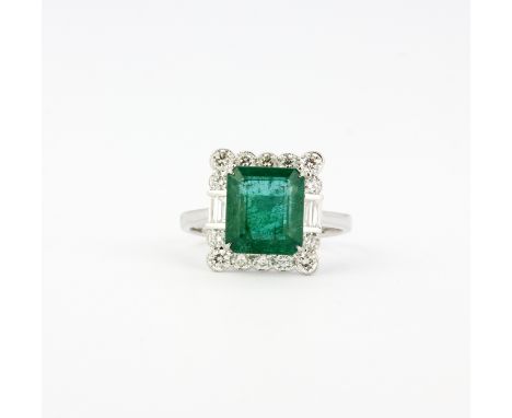 An 18ct white gold ring set with an emerald cut emerald, 1 x 0.8cm, approx. 3.75ct, surrounded by brilliant and baguette cut 