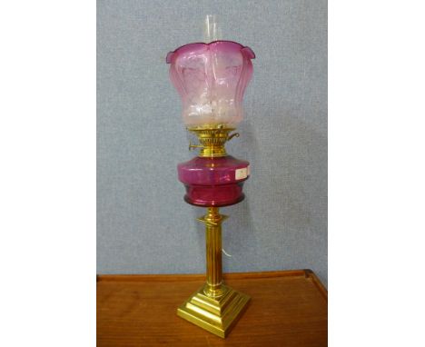 A Victorian brass oil lamp, with cranberry glass reservoir and etched glass shade, converted for electricity 