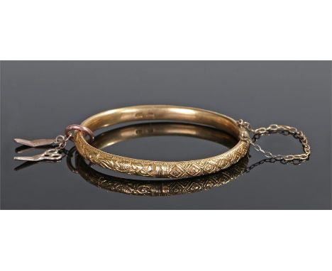 Chinese yellow metal bangle, decorated with a stylised dragon, leaf and flower design, with an attached 9 carat gold charm, t