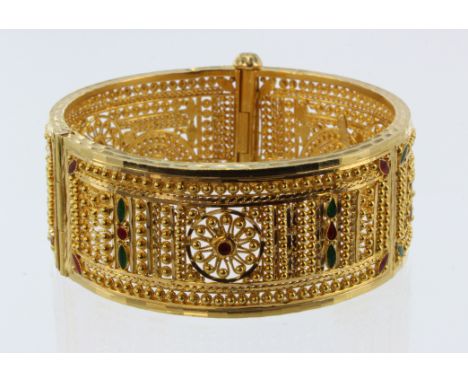 Yellow gold (tests 20ct) wide filigree bangle, with green and red enamel details, width 25mm, hinged with screw clasp, inside