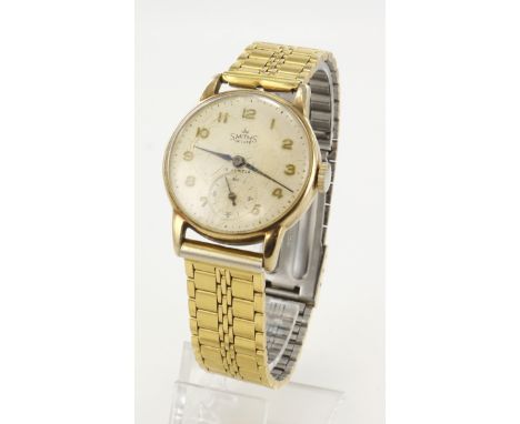 Gents 9ct cased Smiths De Luxe manual wind wristwatch, hallmarked Birmingham 1957. The cream dial with gilt Arabic numerals, 
