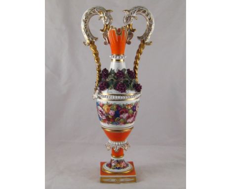A tall ceramic double lipped two handled amphora on a square base with grape vine applique around the neck. Ht.42cm. 