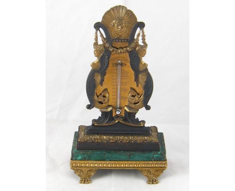 A desk thermometer in classic style, the gilt and oxidised brass figures on malachite base over paw feet supporting the mercu