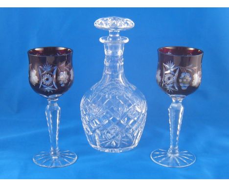 A pair of cut glass wine goblets with ruby flashed bowls and faceted stems together with a cut glass decanter with faceted ne