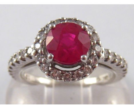 A white metal (tests 18 carat gold) ruby and diamond ring , the ruby measuring approx 6.3mm diameter, ring size K, 5.4 gms.
