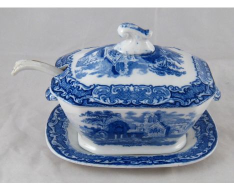 A late 19th. century small blue and white ceramic sauce tureen and stand, transfer printed with a ruined abbey , the base mar