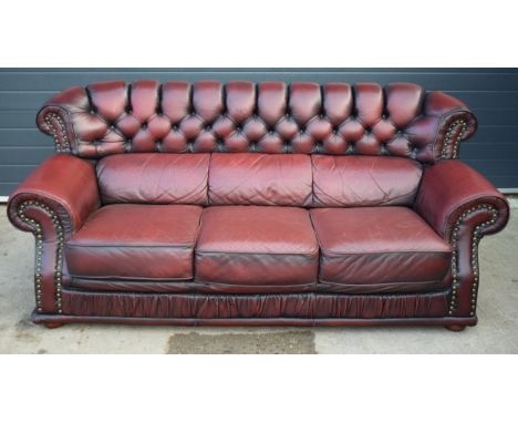 Red oxblood leather chesterfield-style three seater sofa with button-back design and metal beading, 212x95x98cm tall.  In goo
