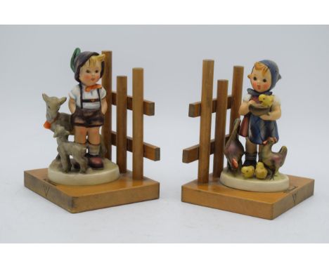 A pair of Goebel / Hummel bookends on wooden bases to include Little Goat Herder No.250 and Feeding Time (2), 14cm tall.  In 