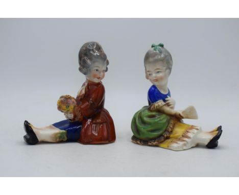 A pair of early Hummel / Goebel bookends of seated girls, one holding a fan, the other flowers, looking towards each other, i