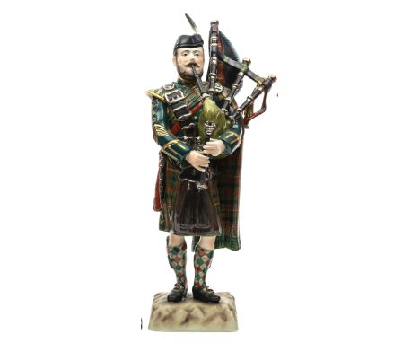 A “Kingsman Collection” painted porcelain figure “Pipe Major Queens Own Highlanders” in full dress, with glengarry cap, playi