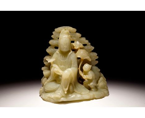 A Chinese pale celadon jade group of Guanyin with a boy, 19/20th C. H.: 13,5 cm - L.: 13,5 cm - W.: 9,5 cm