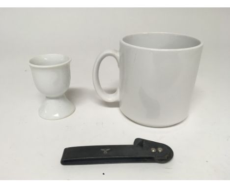 A group of WW2 style items to include a German Army China mug, a kriegsmarine egg cup with 1944 date and a German Army can op