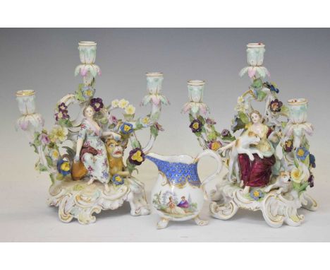 Pair of Dresden porcelain floral encrusted three-branch figural candlesticks, circa 1900, centred on a maiden with hounds, th
