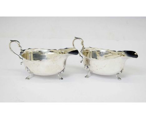 Pair of George V silver sauceboats with scroll handles and standing on three cast feet, sponsor's mark of Adie Brothers Ltd, 