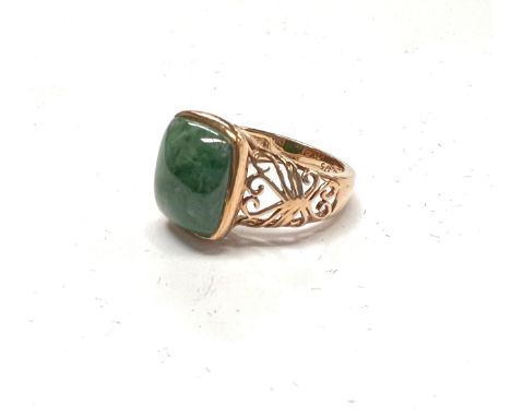 A 9 carat hallmarked gold dress ring set with a square domed jade coloured stone with pierced scroll shoulders, 4.2gm, size L