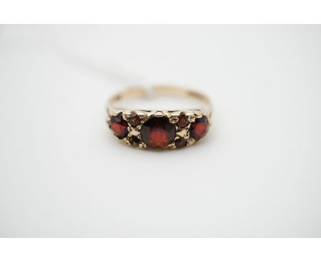 A vintage three-stone garnet dress ring on 9ct gold, the round-cut garnets being sunken and claw set in a graded arrangement,