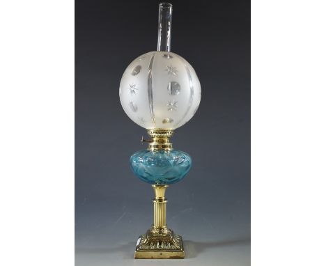 A Victorian brass columnar oil lamp having a blue glass reservoir, and a frosted and cut glass globe