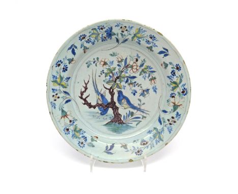 A large delftware charger  c.1760, painted in polychrome enamels with two long-tailed birds, one perched on a flowering branc