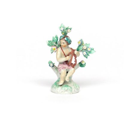A Plymouth figure of a putto  c.1768, seated on a rocky stump before flowering bocage and playing a lyre, some good restorati