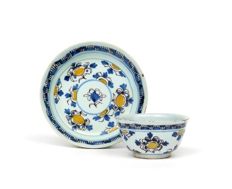 A rare delftware teabowl and saucer  c.1750, finely potted and painted in yellow, blue and manganese with a stylized floral d