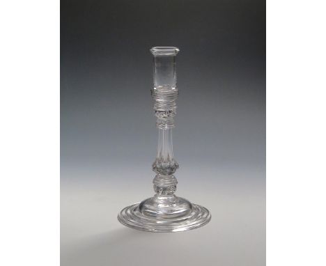 A glass candlestick  c.1740, with tall cylindrical sconce rising to a folded rim, raised on a moulded and collared octagonal 