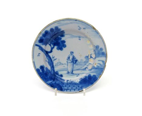 A small Wincanton delftware plate  c.1760, painted in blue with a lady carrying a large basket, standing beneath a sponged tr