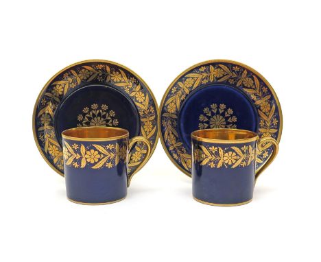 A pair of Sèvres coffee cans and saucers  c.1840, decorated with a continuous formal flowerhead border in gilt on a rich blue