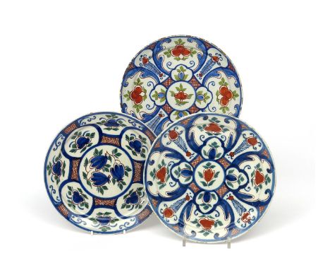 Three London delftware plates  c.1720, variously painted in red, green and blue with panels of stylized flowers reserved on a