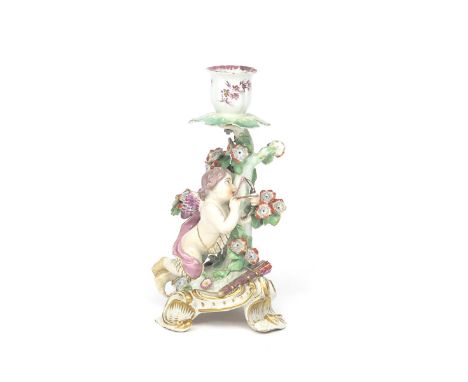 A Chelsea candlestick figure  c.1765, a winged putto kneeling before flowering bocage and pulling back an arrow in a small bo