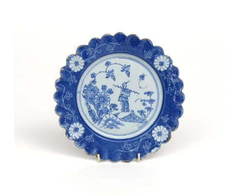 A Lambeth delftware scallop-edged plate  c.1740-50, the well painted with a Chinese man carrying a long stick, looking back o