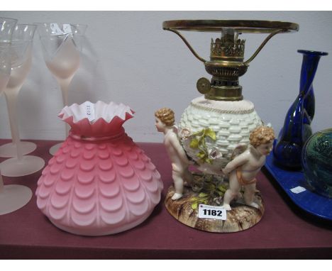 An Early XX Century Sitzendorf Novelty Paraffin Lamp, modelled as three cherubs holding a flower encrusted woven ball, all on