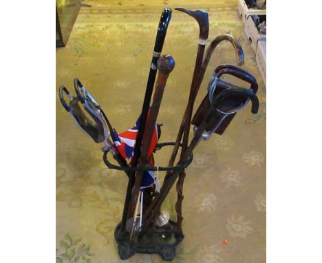 A wrought iron stick stand, together with a quantity of walking sticks.