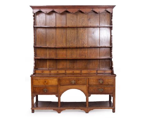 A GEORGE III OAK DRESSER with a three tier Delft rack above five spice drawers, five drawers with brass swan neck handles and