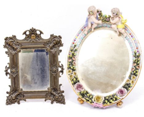 AN EARLY 20TH CENTURY PORCELAIN ORNAMENTAL MIRROR decorated with cherubs and flowers on gilt painted feet, with indistinct co