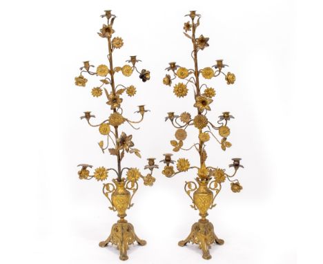A PAIR OF ANTIQUE GILT METAL DECORATIVE FLORAL CANDLESTANDS in the form of scrolling leaves and flowers, on tripod bases, 105