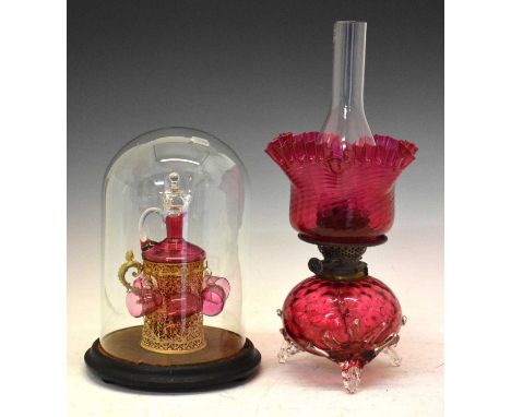 Cranberry glass liqueur set, comprising bottle in gilt wirework sleeve, 22.5cm high, with six cups, on ebonised stand beneath