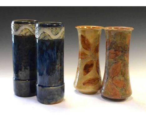 Two pairs of Doulton Lambeth stoneware vases, the first of sleeve form with foliate collar and blue glaze, impressed 8137, 25