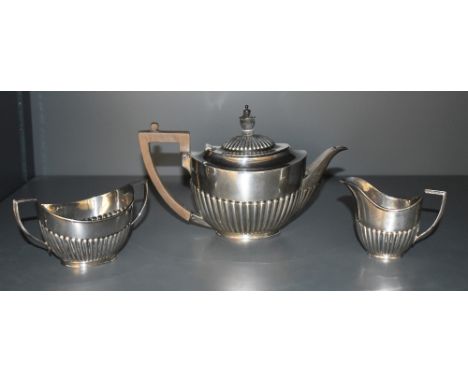 An Edwardian silver three-piece teaset, comprising teapot, sugar and cream, of oval half fluted design with angular handles, 