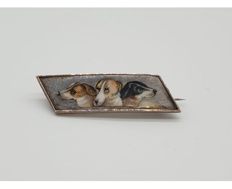 (NB) A Victorian enamel trapezoid shaped brooch, painted with three dog's heads, 38mm. 