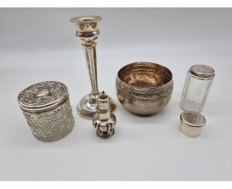 A group of silver items, comprising; two silver lidded glass jars; a silver pill box; a silver candlestick; a silver pepperet